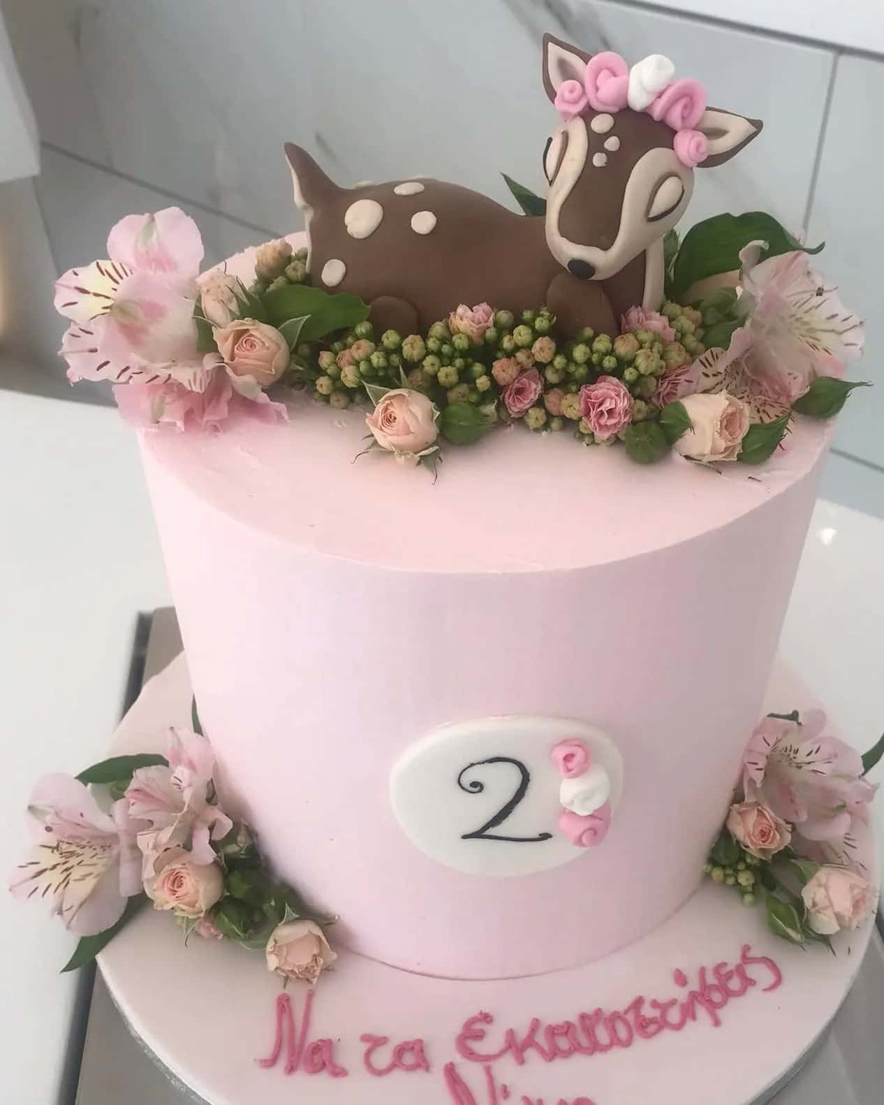 Pale pink birthday cake crowned with fresh roses and a hand-modelled fawn