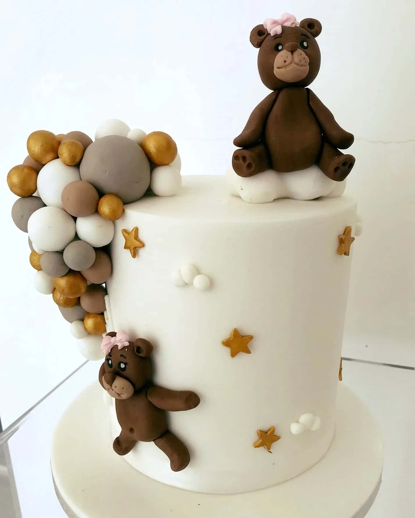 White christening cake with hand-modelled teddy bears, gold stars and a cascade of sugar spheres